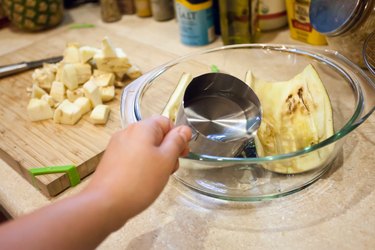 person pouring water into a baking dish with white eggplant shells