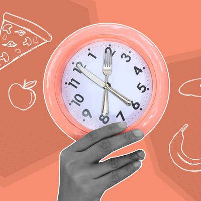 Hand holding eating utensil clock with food in background