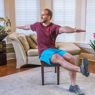 Man doing a seated abdominal twist exercise during a full-body chair workout