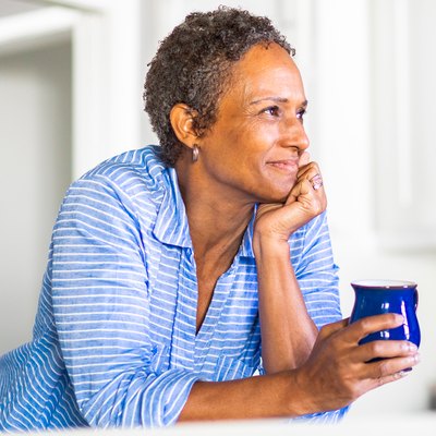 middle-aged woman holding a cup of coffee looking content