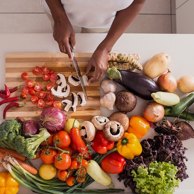 Woman on a weight-loss diet chopping a variety of vegetables in her kitchen