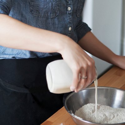 Woman pouring milk in bowl.