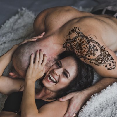 Happy young couple in underwear having fun in bed