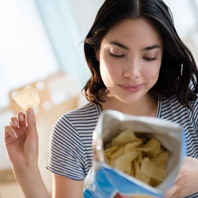 Woman eating processed foods processed snacks like potato chips health risks
