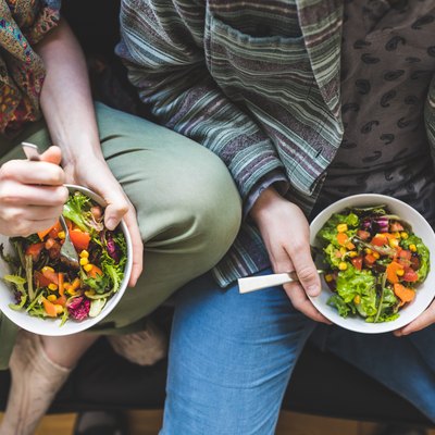 Couple eating healthy salad at home on the sofa