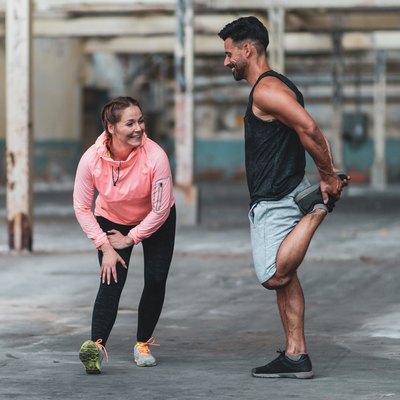 Woman and man stretching out calf pain from running