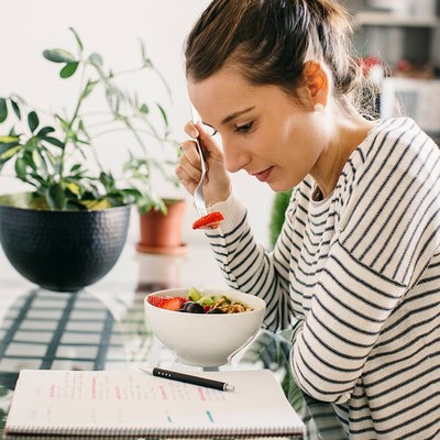 Woman eating breakfast and reading food journal