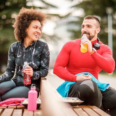 Couple on bench drinking energy drinks.