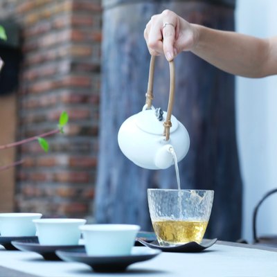 Person's hand pouring green tea into cup