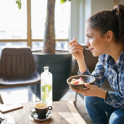Woman eating yogurt with coffee in the morning
