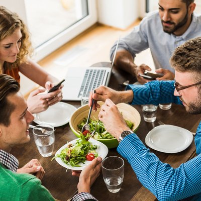 Women and men having a working lunch, man serving salad