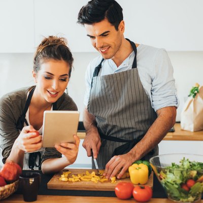 Woman and man in kitchen using cooking tips on ipad