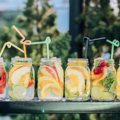 six fruity waters with sliced fruit and straws on table