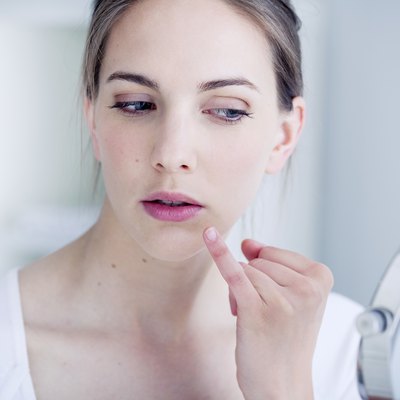 Woman looking at herself in the mirror for cold sore