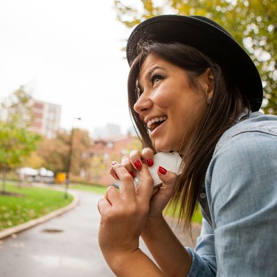 Woman sitting outside resting her Chin against her phone