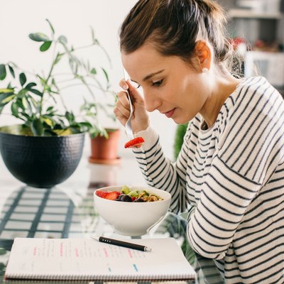 Woman eating breakfast and reading food journal