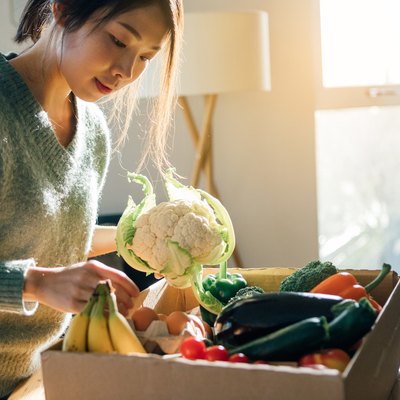 一个女人打开装着卷心菜的杂货纸盒