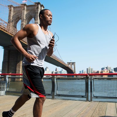 Man running in New York City near Brooklyn Bridge using a half-marathon training schedule for beginners.
