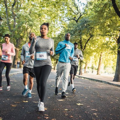 Runners in a park competing in a race following a marathon training schedule for beginners