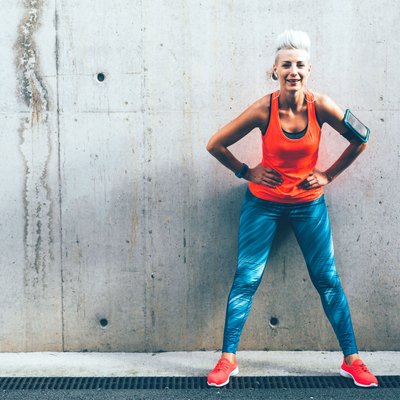 Woman standing against a concrete wall wearing colorful activewear