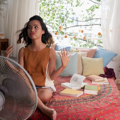 woman can’t sleep during the hot summer so she sits in front of a fan