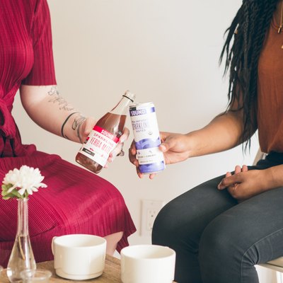 Two women clinking sparkling tea glasses