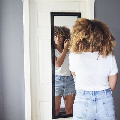 Woman looking in mirror at hairline