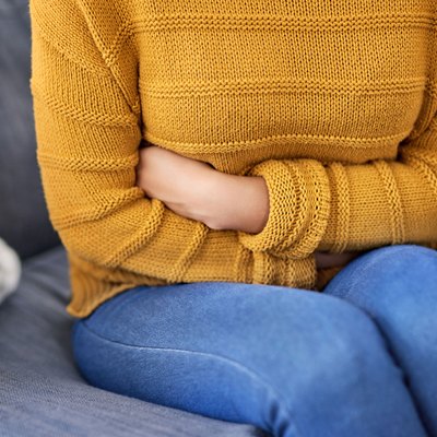 Woman sitting on a couch experiencing bloating after colonoscopy