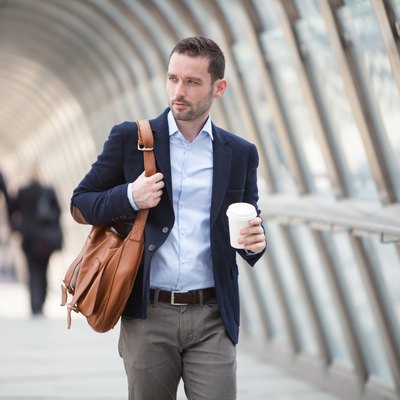 Young attractive man with stomach ulcer drinking coffee on his way