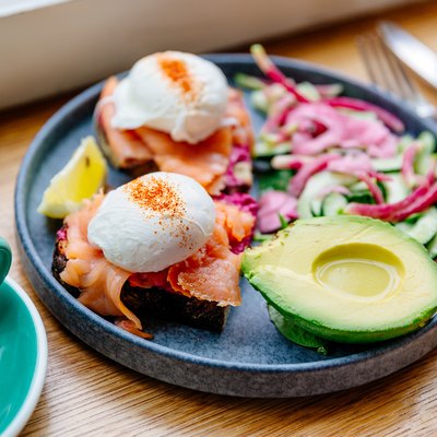 poached eggs with salmon and avocado on a blue plate