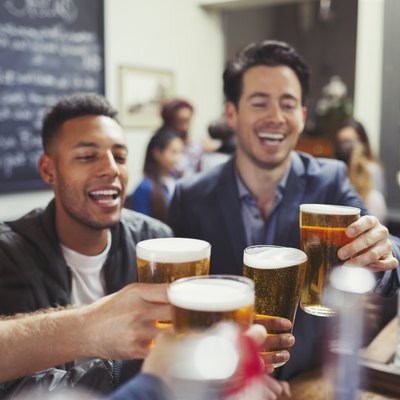 Men friends toasting beer glasses at bar