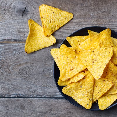 Nachos, corn chips on black plate. Wooden background. Top view. Copy space.
