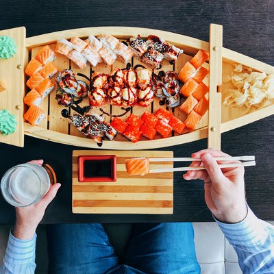 Man eating sushi from a sushi boat in Japanese restaurant, directly above personal perspective view