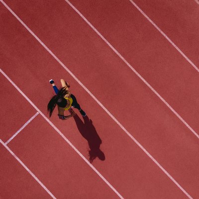 Female runner listening to music and running on sports track