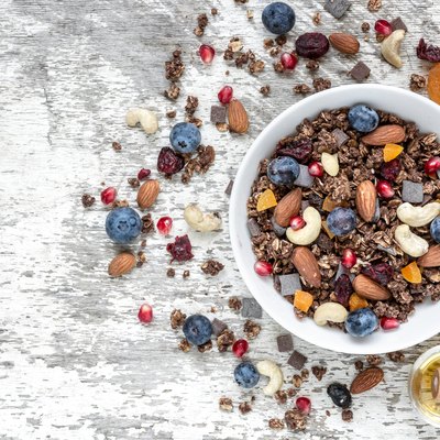 bowl of chocolate oat granola or muesli with nuts, berries, dried fruits and honey