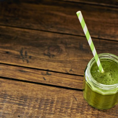 Wheat grass juice in a mason jar on a rustic aged wood table top.