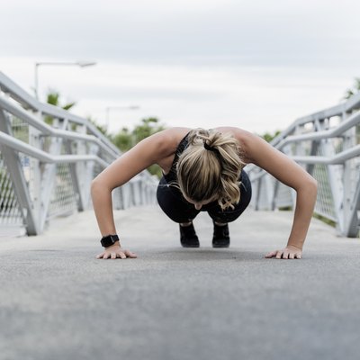 Sporty woman doing push ups, working out on a bridge