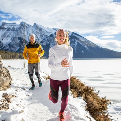 Two people exercising for cross-country running in winter jogging on snowy path