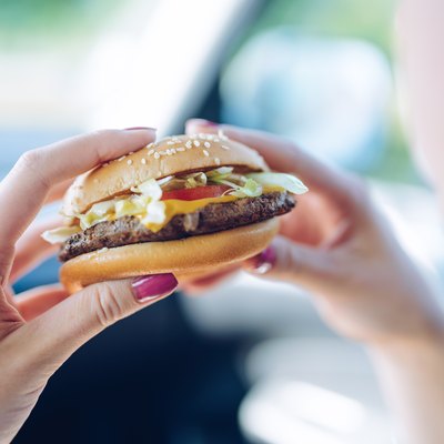 Girl thinking about whether there are antibiotics in meat of her fast-food hamburger