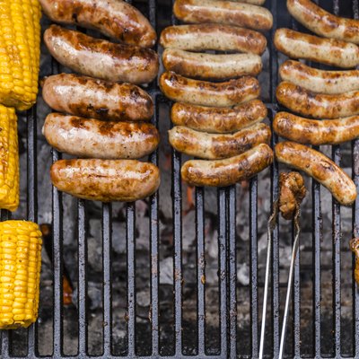 Different meat, maize and fried sausages on barbecue grill