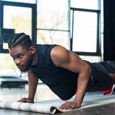 muscular african american sportsman doing push ups and looking away in gym