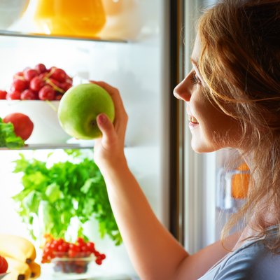 Woman peering in fridge wondering how to store vegetables