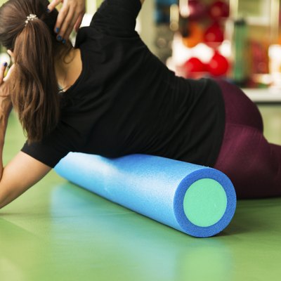 Woman doing foam roller exercise for lats on a floor
