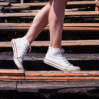 Woman model feet wearing sneakers walking down the bench