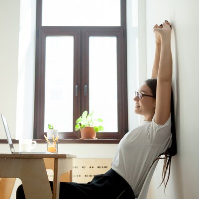 Attractive young businesswoman relaxing, stretching at desk in home office