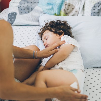 Mother caress her baby in bed