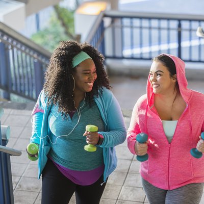 Two young women exercising, powerwalking up stairs