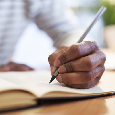 Man's hand drawing in a notebook