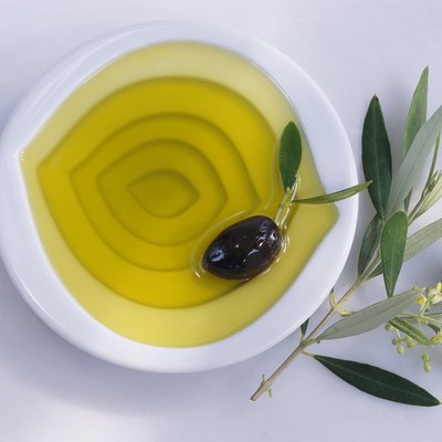 Bowl of olive oil, olives, twig of olive tree