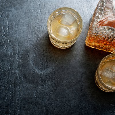 Glasses of bourbon with ice cubes on stone table. Top view